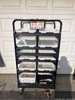 Front view of the black rolling cart holding white plastic storage bins, showing wear and dirt marks.
