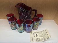 Full set with ruby red carnival glass pitcher and six matching glasses with iridescent finish, displayed with a certificate of limited edition from E. Ward Russell