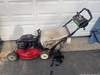 Full side view of the red Toro riding lawn mower showing the kit including the engine and grass catcher bag.