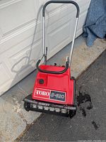 Front view of the red Toro S-620 snow thrower showing the handle and body with Toro logo and model number.