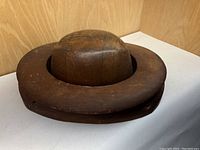 Dome top of wooden hat mold placed on ring base, side angle showing shape and wear.