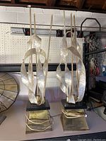 Pair of vintage lamps with twisted pearlescent ribbon decorations on metallic bases shown together from front view.