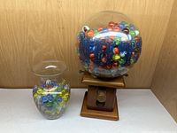 Wide shot showing both glass containers with vintage marbles inside against wooden background.