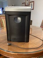 Full view of Fellowes DM8C paper shredder showing black body, silver top panel and power cord on table.