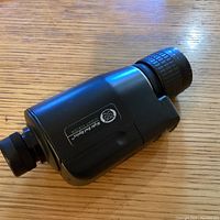 Black Night Owl Optics night vision monocular shown on a wooden surface.