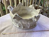Side view of the large ceramic tureen showing multiple standing lambs as part of the ornate exterior design. Measuring tape nearby shows size approx 16 inches.