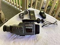 Sony Handicam CCD-F36 camcorder on white surface with power adapter and small camera light nearby.