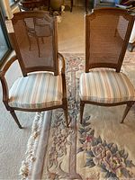 Two Henredon dining chairs visible, one with armrests (captain chair) and one without. Both chairs have cane lattice backs and striped cushioned seats.