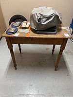 Full frontal view of the wooden table showing surface and legs with some objects on top covered or placed around but not included.