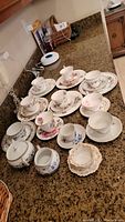 Full set of 10 teacups with saucers and additional plates plus sugar and creamer displayed on counter.