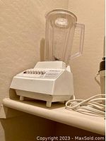 Photo of white vintage blender with clear plastic container and power cord, showing front and buttons.