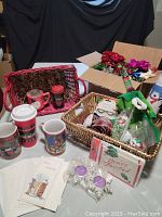Photo showing assorted Christmas mugs, woven baskets, greeting cards, and small candles.