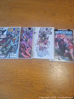 Four Outsiders comics in plastic sleeves on a wooden table, showing detailed cover art with superheroes and villains.