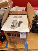 Closed cardboard box with instruction manual showing an image of the electric bag closing machine model GK9-890 along with different models listed.