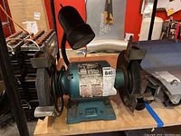 Front view of Ohio Forge bench grinder showing two grinding wheels and its mounted work light.