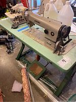 Full view of sewing machine head on table, oil bottles in background