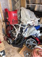 Overall shot of red tubular steel leaf vacuum with white Briggs & Stratton engine, black hoses, pulleys and plastic hopper top