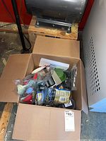 Box of assorted pet supplies including catnip toys, dog treats, bowls, and bags