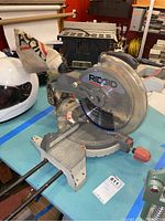 Overall view of the Ridgid miter saw showing the blade, dust bag, and base with angle markings.