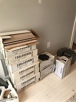 Stack of 12 labeled boxes of 100x400mm wall tiles against a wall