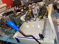 Overall view of the Goldstar portable swatch cutter with blue handle and upholstery tools on the workbench.
