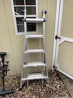 Full view of ladder in A-frame configuration leaning against shed