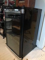 Front right angled view showing glass door, chrome handle, and interior metal shelves.