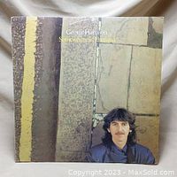 Front cover of George Harrison's Somewhere in England vinyl album showing the artist and stone pattern artwork.