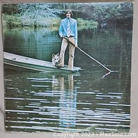 Front cover of the vinyl record album showing James Taylor on a boat with a dog in a calm water setting.