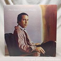 Front cover of Paul Simon Greatest Hits vinyl record album showing Paul Simon sitting in a chair.