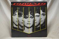 Front cover of the Toronto 'Head On' vinyl record album showing black and white photos of five band members separated by vertical yellow lines on a black background.