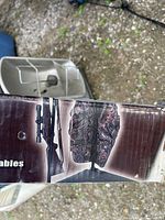 Box showing folding cot with camouflage tent and rifle scope holder.