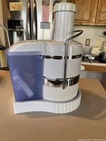 Photo of Jack LaLanne Power Juicer side view showing white body with blue juice container and metal lock arm