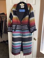 Front view of multi color striped coat with zipper and side pockets.