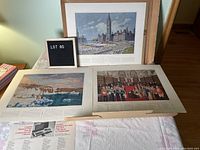 Several loose art prints displayed, including scenes of Canadian Parliament and historic events, laid out on a table with original shipping box visible.