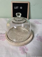 Covered cheese plate showing marble base and glass dome from a frontal angle.