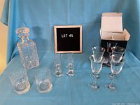 Photo showing crystal decanter, two tall shot glasses, two short tumblers, four stemware glasses, and open box in background.