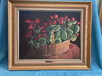 Framed print showing a basket of red flowers and green leaves with shadow and light effects.