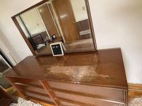 Front view of dresser and attached mirror showing overall condition and top surface damage.