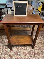 Front view of the vintage wooden side coffee table showing the rectangular top and lower shelf with visible wear.