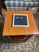 Top-down view of square wooden side table showing top surface and part of shelves underneath.