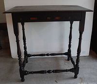 Front angle showing full view of black wooden spindle leg accent table with pronounced decorated inlays.