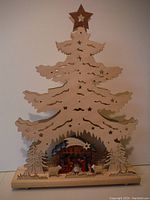 Front view of wooden nativity scene shaped as a Christmas tree with star topper and figures beneath.