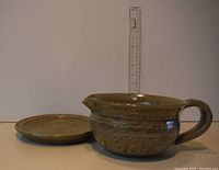 Green glazed ceramic gravy dish alongside matching plate, with ruler shown for size reference