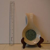 Ceramic spoon rest with green rooster design and a ruler placed beside it for size reference, displayed on a wooden stand (not included).