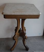 Full view of wooden side table with harp shaped legs supporting square marble top.