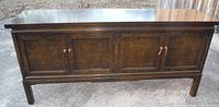 Front view of whole Thomasville wood credenza with four paneled doors and classic dark finish taken outdoors.