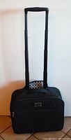 Photo of the black quilted rolling commuter bag standing upright with fully extended handle against a plain background