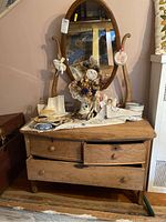 Front view of oak dresser vanity with bow front three drawers and oval swivel mirror showing wear and scratches, with vintage decorative items on top.