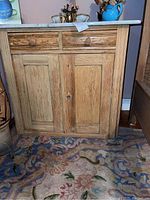 Front view of pine wood dry sink showing two drawers above a double-door cabinet with keyhole and wooden knobs.